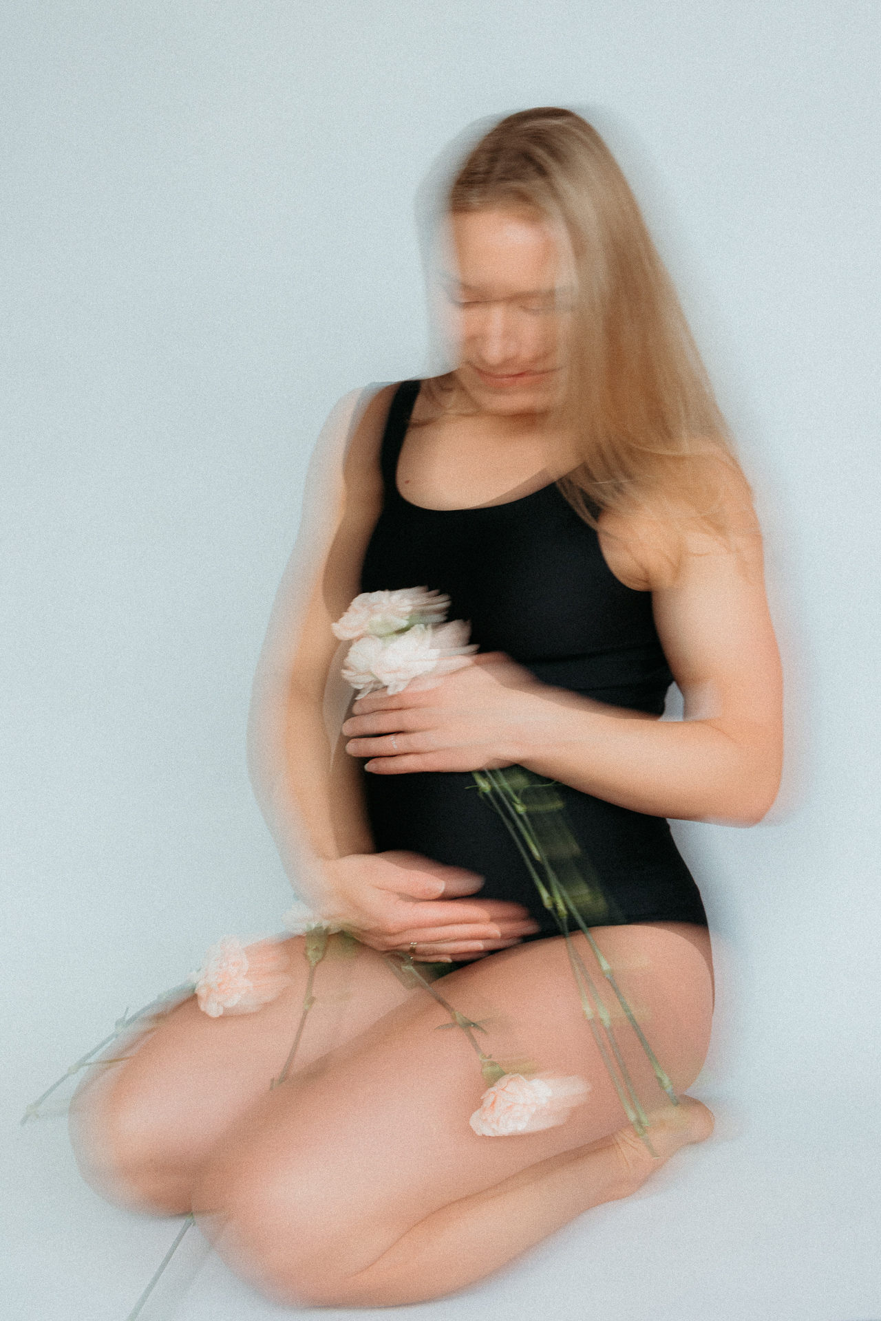 kobieta w czarnym body siedzi z kwiatkami w dłoni w domu w Krakowie