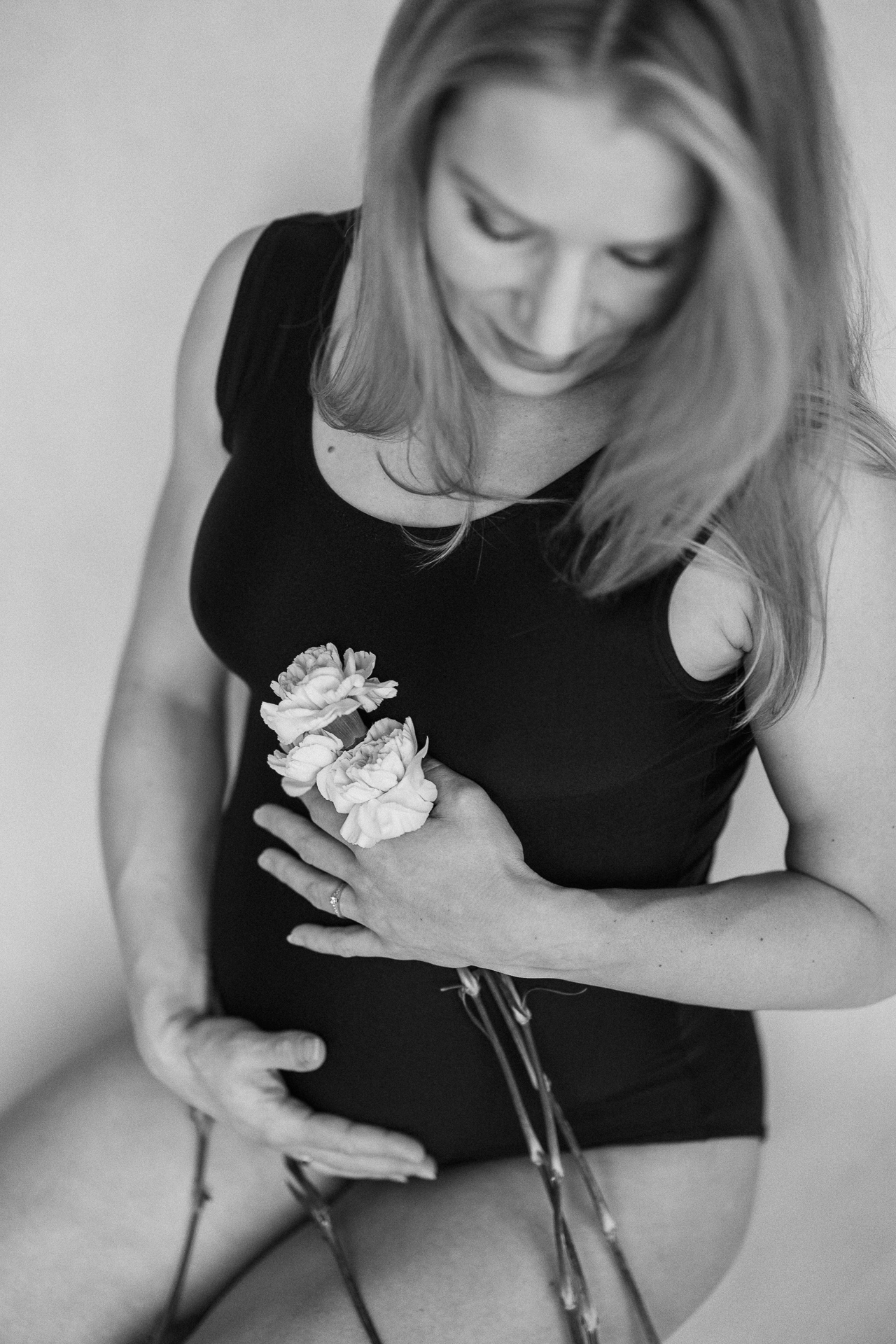 kobieta w czarnym body siedzi z kwiatkami w dłoni w domu w Krakowie