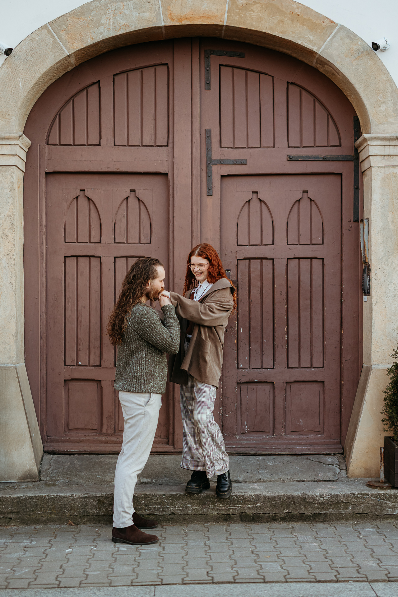 Mężczyna całuje w rękę uśmiechniętą kobietę przy drzwiach, Kraków