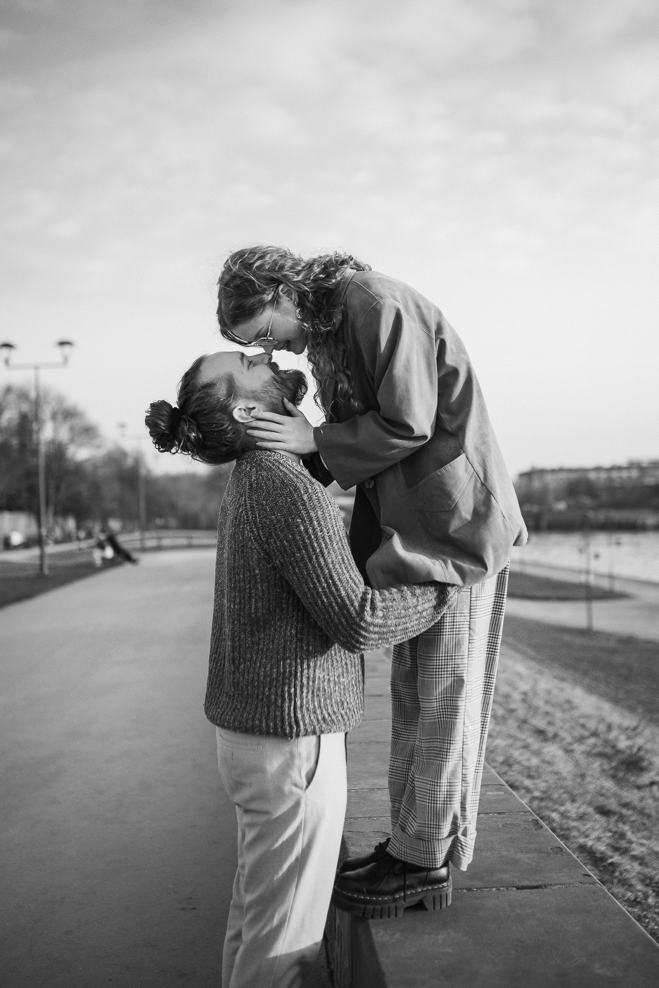 kobieta stoi na murku i przytula mężczyznę, który stroi na drodze w Krakowie